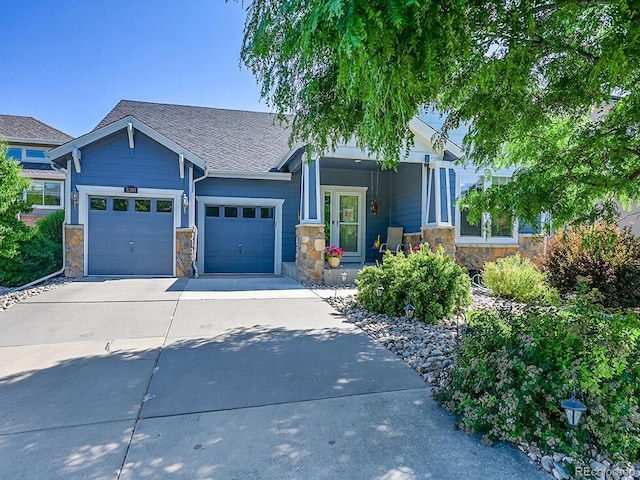 5309 W Hoover Dr, Littleton, CO 80123 - view of front of home featuring concrete driveway, stone siding, an attached garage, and covered porch