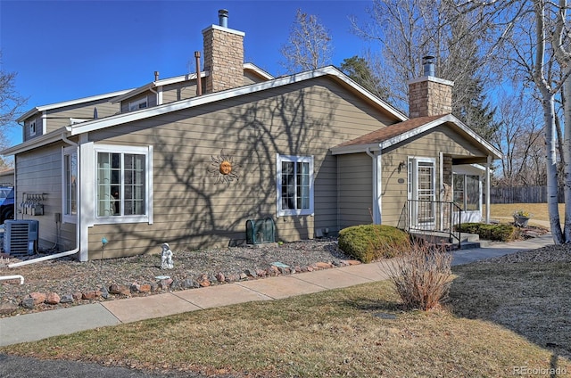 view of side of home featuring central AC and a chimney