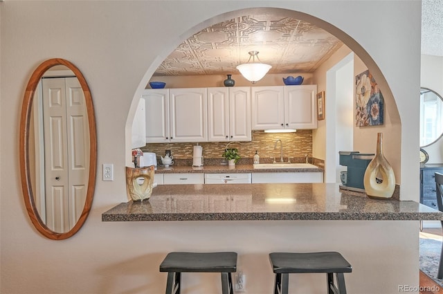 kitchen featuring white cabinets, a breakfast bar area, an ornate ceiling, and decorative backsplash