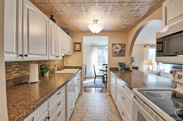 kitchen featuring tasteful backsplash, arched walkways, an ornate ceiling, appliances with stainless steel finishes, and a sink