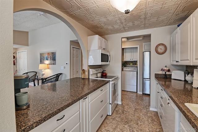 kitchen with white appliances, white cabinetry, baseboards, washer / clothes dryer, and an ornate ceiling