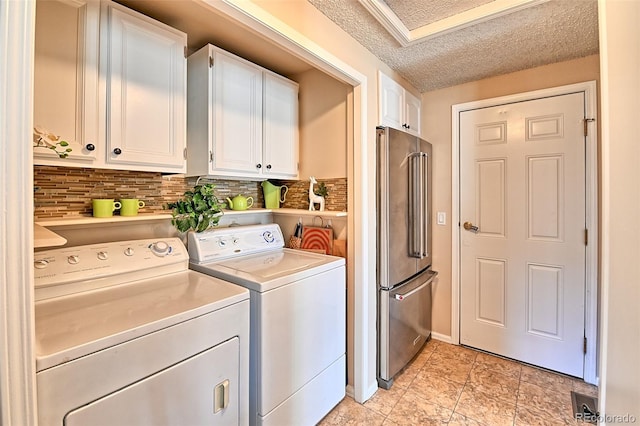 washroom with laundry area, washer and clothes dryer, and a textured ceiling