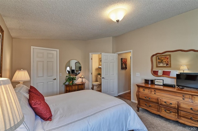 carpeted bedroom featuring a textured ceiling, connected bathroom, and baseboards