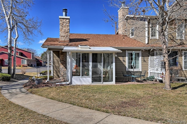 rear view of house with a sunroom, a lawn, a chimney, and fence