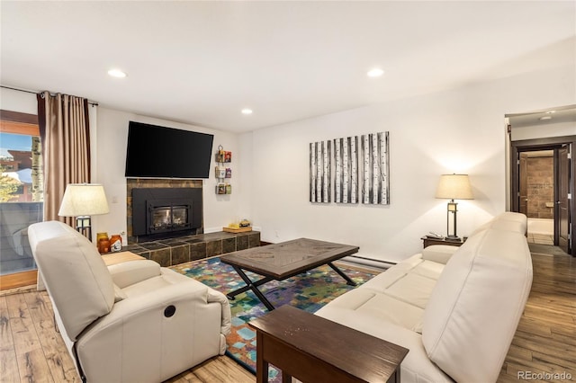 living room featuring recessed lighting, wood finished floors, and a tiled fireplace