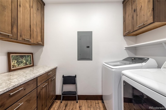 clothes washing area with baseboards, light wood-style flooring, electric panel, cabinet space, and separate washer and dryer