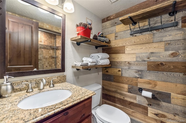 full bath with wooden walls, a textured ceiling, toilet, and vanity