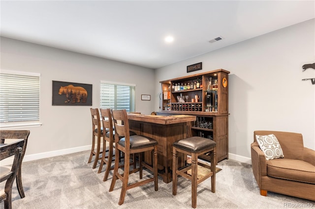 bar with light carpet, a dry bar, and baseboards