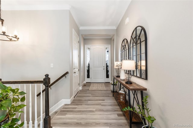 entryway with light wood-style floors, crown molding, and baseboards