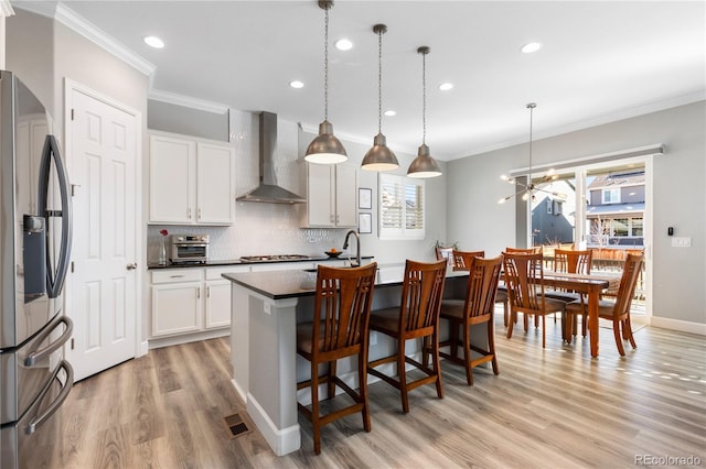 kitchen with wall chimney range hood, crown molding, stainless steel appliances, and backsplash