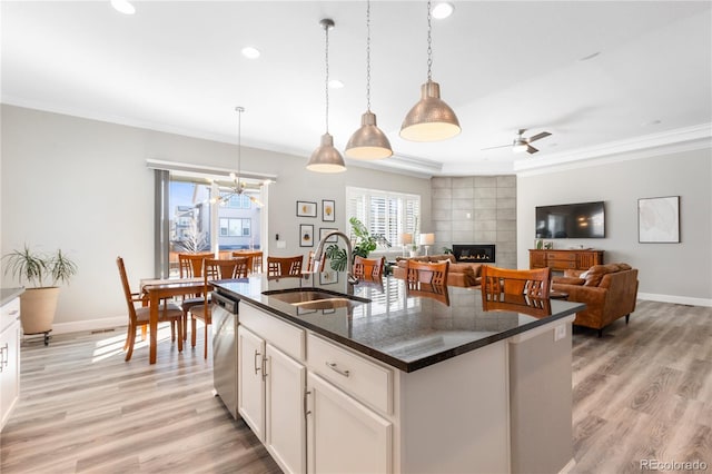 kitchen with crown molding, a fireplace, a sink, and light wood-style flooring