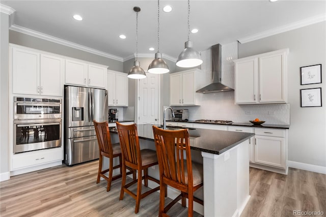 kitchen featuring stainless steel appliances, dark countertops, ornamental molding, and wall chimney exhaust hood