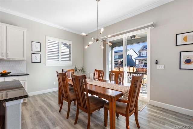 dining space featuring ornamental molding, light wood finished floors, baseboards, and an inviting chandelier