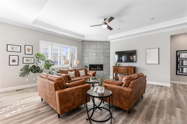 living area with light wood-type flooring, baseboards, ornamental molding, and a tile fireplace