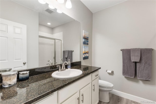 bathroom with a stall shower, baseboards, toilet, wood finished floors, and vanity