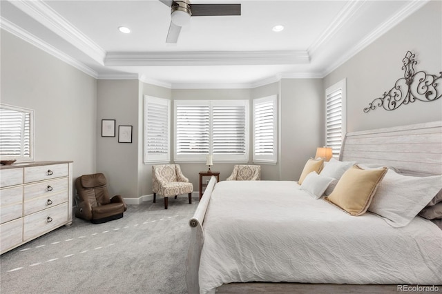 carpeted bedroom featuring ornamental molding, a tray ceiling, and multiple windows