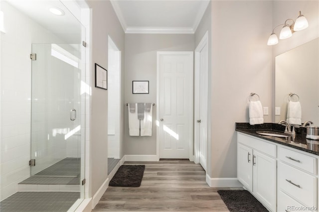 bathroom with ornamental molding, a stall shower, vanity, wood finished floors, and baseboards