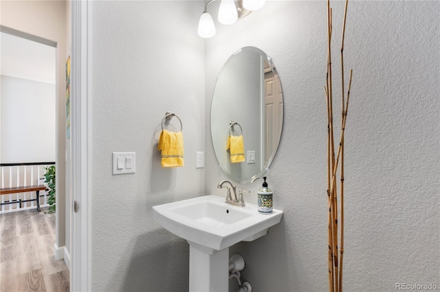 bathroom with a textured wall and wood finished floors