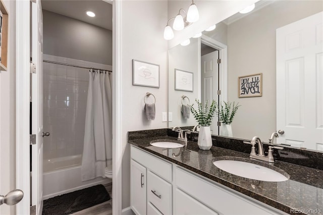 bathroom with double vanity, shower / bath combo, a sink, and toilet