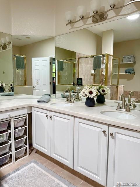 601 Clarendon Loop, Castle Pines, CO 80108 - bathroom featuring double vanity, a shower with door, and tile patterned flooring