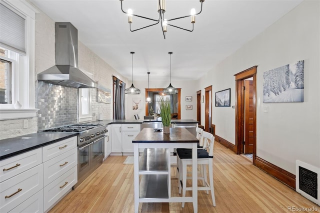 1554 N Pennsylvania St, Denver, CO 80203 - kitchen with visible vents, dark countertops, wall chimney exhaust hood, a peninsula, and double oven range