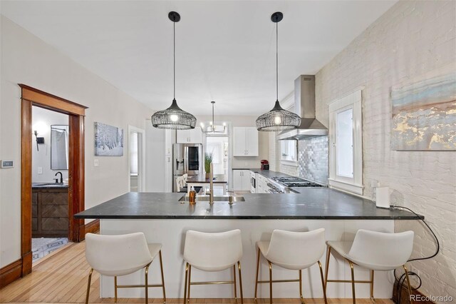 1554 N Pennsylvania St, Denver, CO 80203 - kitchen featuring stainless steel fridge, white cabinets, dark countertops, wall chimney range hood, and a sink
