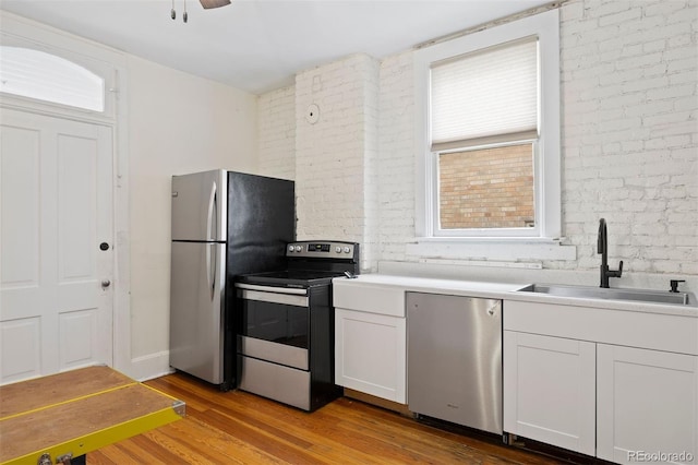 1554 N Pennsylvania St, Denver, CO 80203 - kitchen featuring stainless steel appliances, a sink, brick wall, and wood finished floors