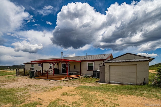 235 Blazing Saddle Trl, Cotopaxi, CO 81223 - back of property featuring central AC unit, metal roof, dirt driveway, an attached garage, and a standing seam roof
