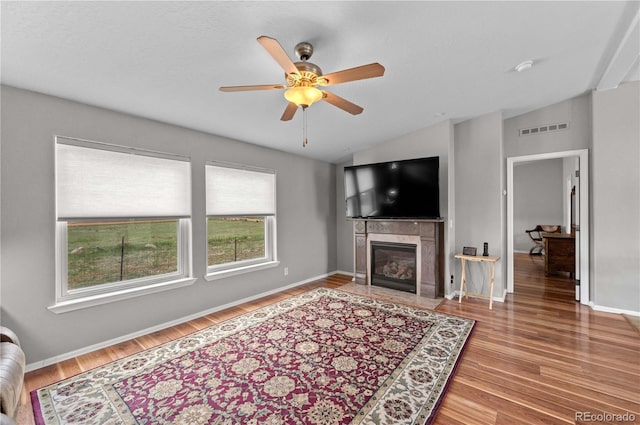 235 Blazing Saddle Trl, Cotopaxi, CO 81223 - living room featuring wood finished floors, ceiling fan, vaulted ceiling, a tiled fireplace, and baseboards