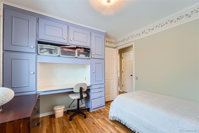 bedroom with light wood-type flooring, built in desk, and ornamental molding