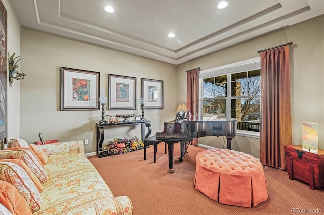 sitting room featuring a raised ceiling and carpet flooring