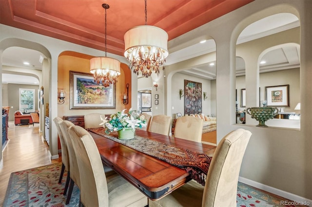 dining space featuring a raised ceiling, an inviting chandelier, and light hardwood / wood-style flooring