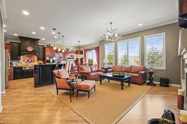 living room with ornamental molding, a notable chandelier, and light hardwood / wood-style flooring