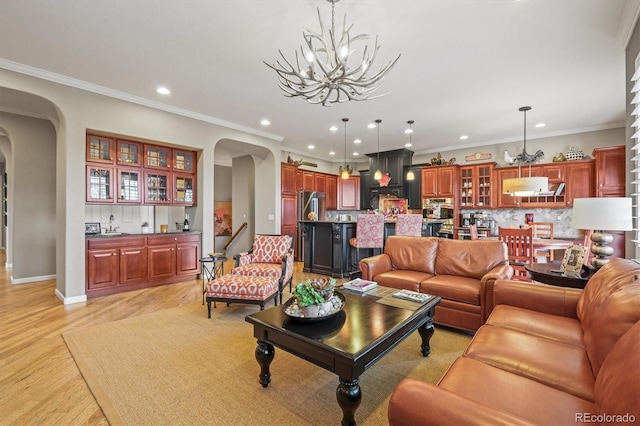 living room with crown molding, a chandelier, and light hardwood / wood-style floors