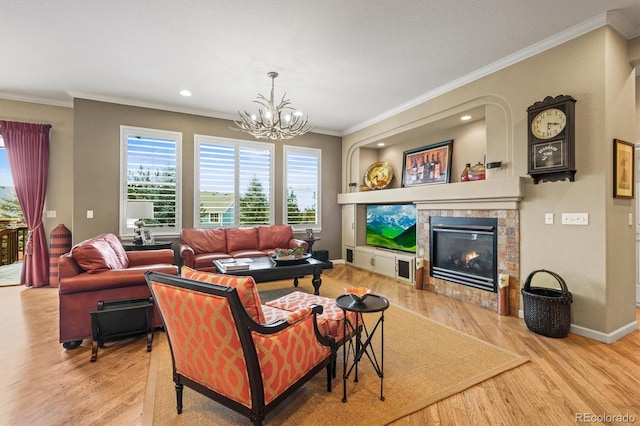 living room featuring ornamental molding, light hardwood / wood-style floors, a tile fireplace, and a notable chandelier