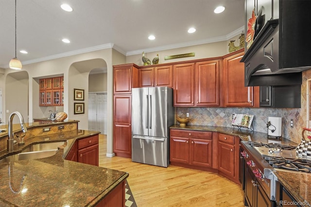 kitchen featuring sink, appliances with stainless steel finishes, dark stone countertops, extractor fan, and decorative light fixtures