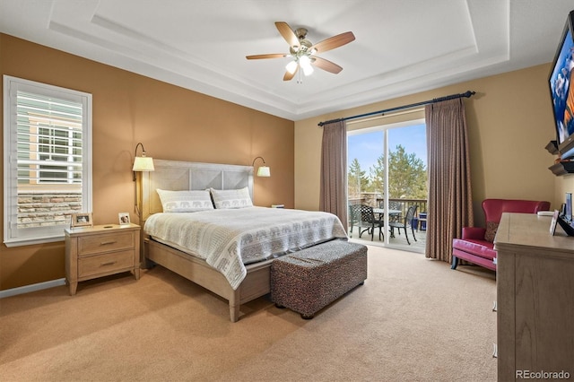 bedroom with access to exterior, a tray ceiling, light colored carpet, and ceiling fan