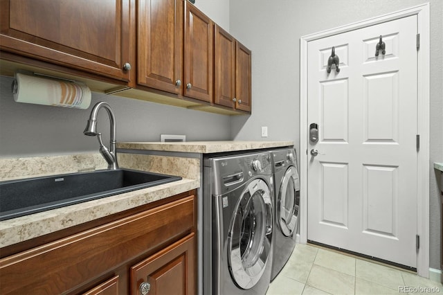 clothes washing area with cabinets, sink, light tile patterned floors, and washing machine and clothes dryer