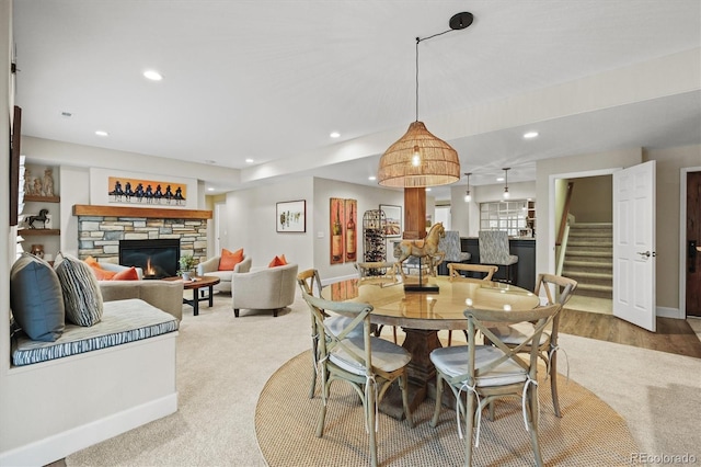 carpeted dining area with a stone fireplace