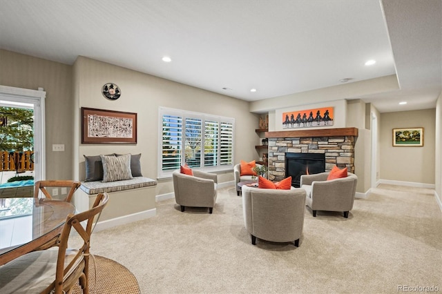 carpeted living room featuring a stone fireplace