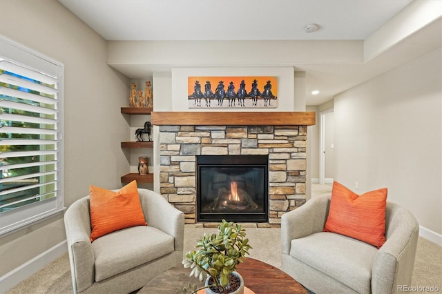 carpeted living room with a stone fireplace