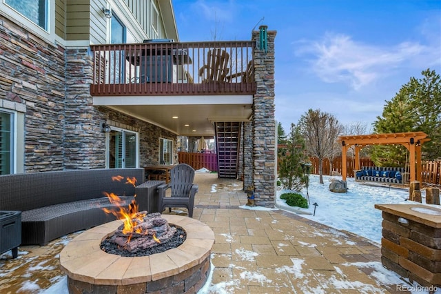 snow covered patio featuring a balcony, an outdoor living space with a fire pit, and a pergola