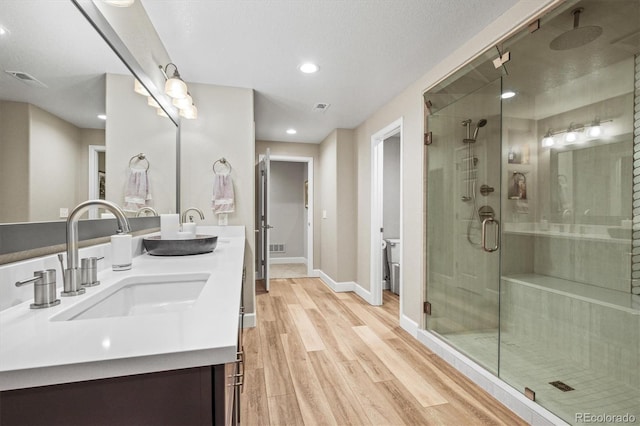 bathroom with vanity, hardwood / wood-style floors, and a shower with door