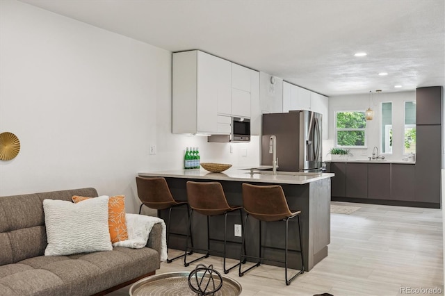 2059 S Balsam St, Lakewood, CO 80227 - kitchen featuring stainless steel appliances, a peninsula, open floor plan, a breakfast bar area, and modern cabinets