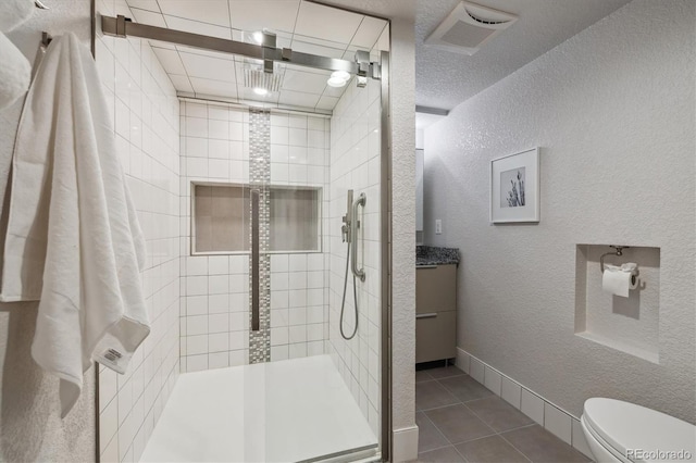 2059 S Balsam St, Lakewood, CO 80227 - bathroom featuring a shower stall, toilet, tile patterned flooring, vanity, and a textured wall