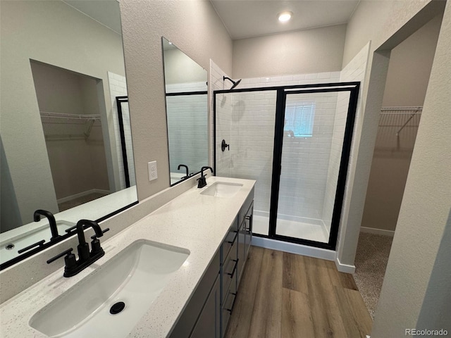 full bathroom featuring a sink, a stall shower, wood finished floors, and double vanity