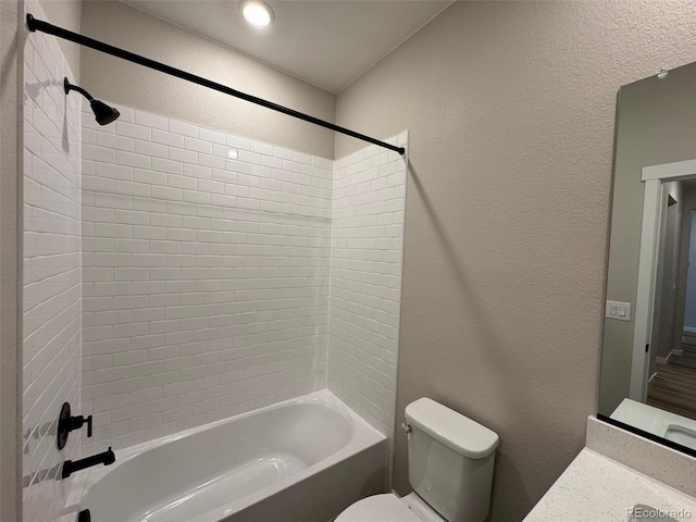 bathroom featuring toilet, washtub / shower combination, and a textured wall