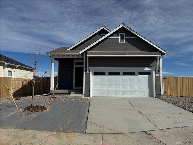 view of front of house featuring concrete driveway, fence, and a garage