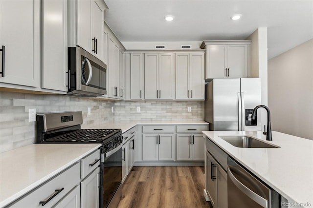 9376 Yampa Ct, Commerce City, CO 80022 - kitchen featuring wood finished floors, light countertops, a sink, stainless steel appliances, and backsplash