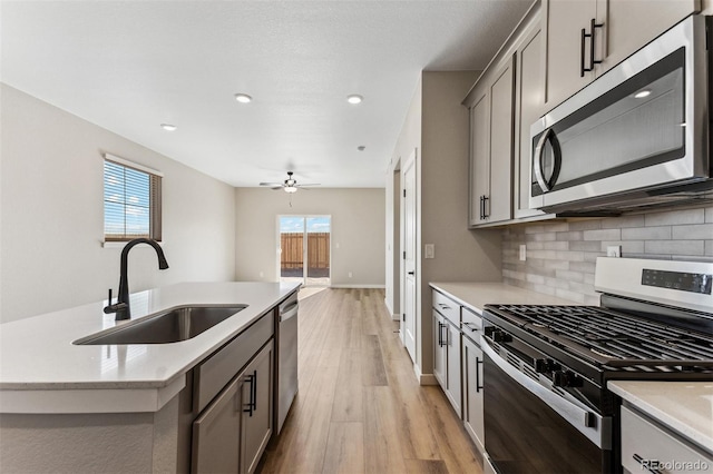 9376 Yampa Ct, Commerce City, CO 80022 - kitchen with a sink, light wood-type flooring, appliances with stainless steel finishes, gray cabinets, and decorative backsplash